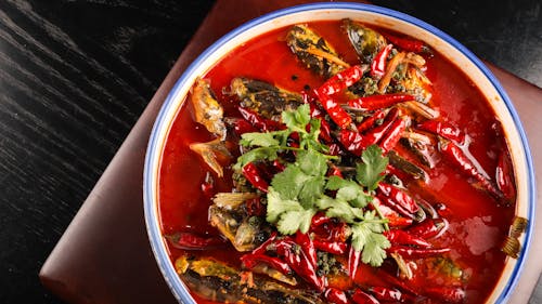 Free A bowl of red soup with fish and herbs Stock Photo