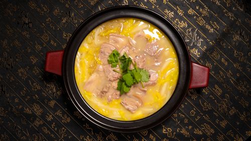 Top view of a delicious traditional meat stew garnished with herbs, served in a black ceramic pot