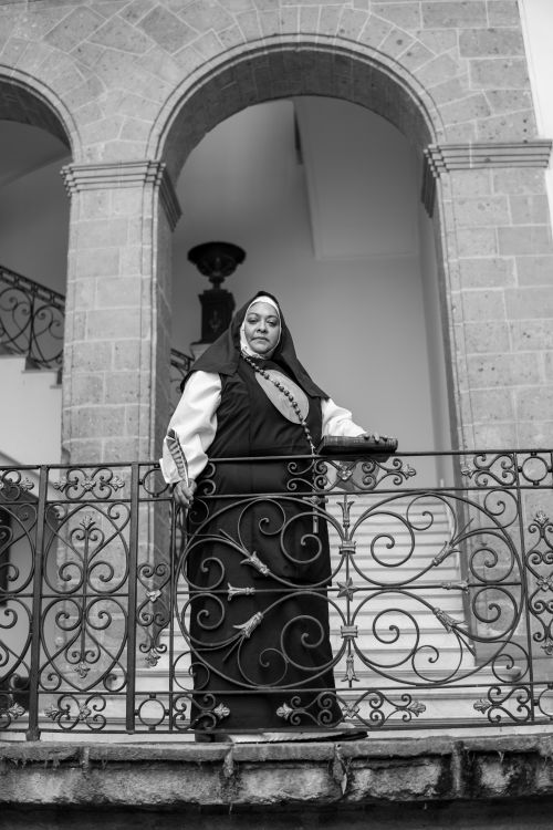 Free Black and white portrait of a nun in Mexico City standing on a wrought iron balcony. Stock Photo