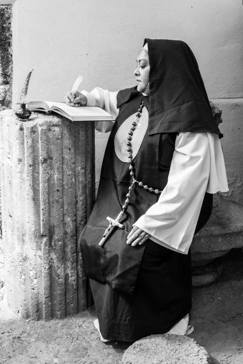 Free A nun in traditional habit writing by candlelight in Mexico City. Stock Photo