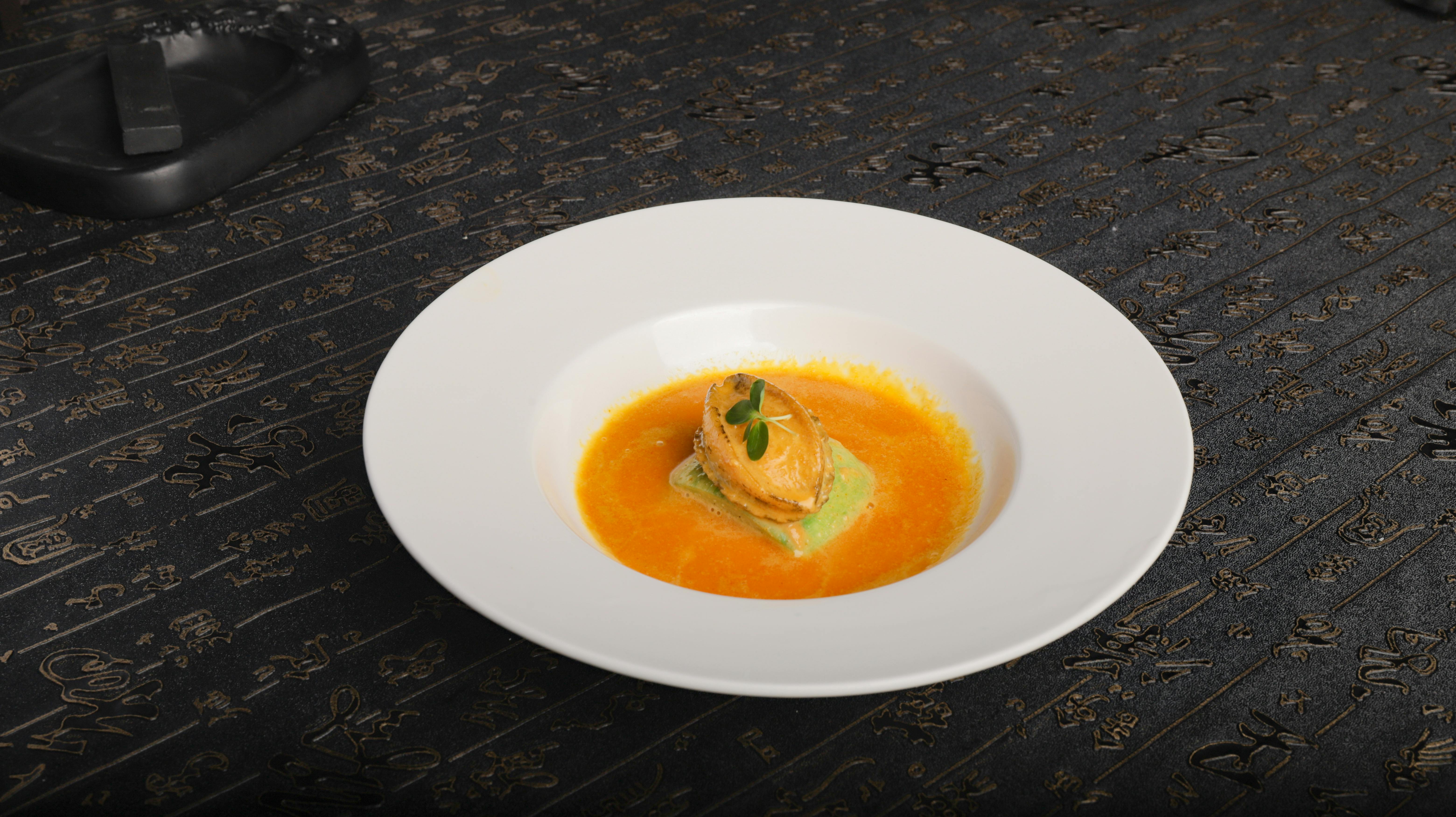 Elegant seafood dish served in a vibrant orange sauce on a decorative table.