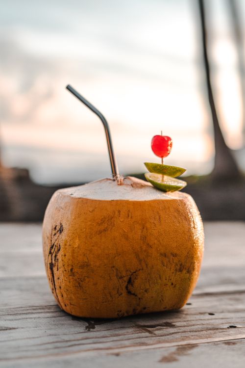 Free Coconut drink with straw on beach, perfect for summer sunsets. Stock Photo