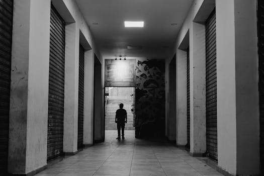 A lone silhouette in a black and white hallway creates a dramatic and moody scene.