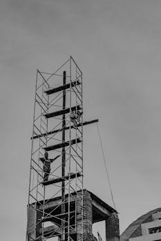 Construction workers on scaffolding at an urban site, monochrome shot.