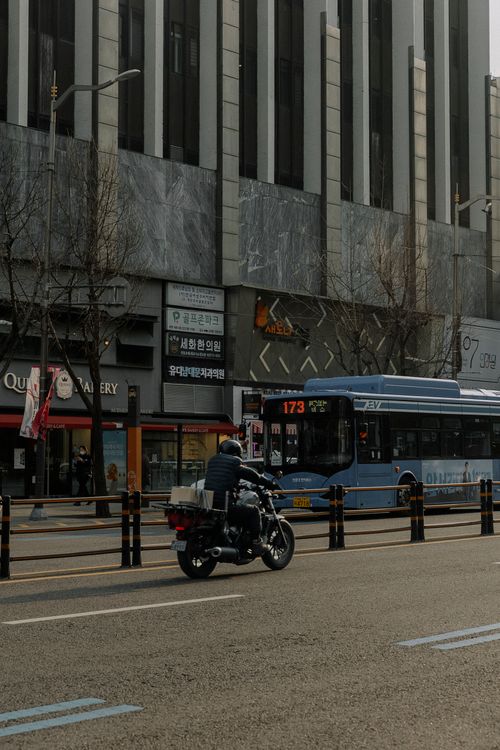 Free A modern city street with a bus and motorcyclist in motion, capturing urban life. Stock Photo