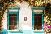 Charming window façade in Tequisquiapan, Mexico with blooming flowers and vibrant colors.