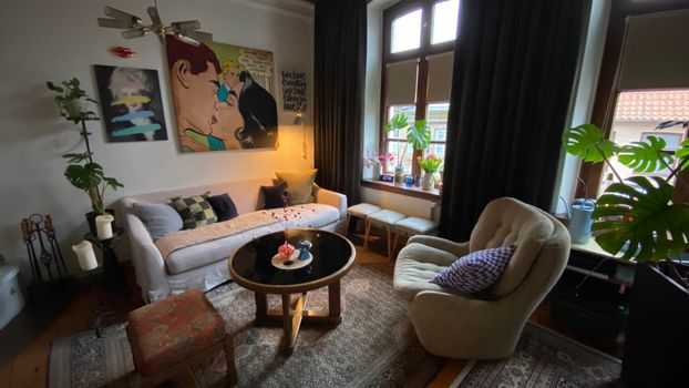 Inviting living room in Mölln with modern art, elegant furniture, and lush potted plants.