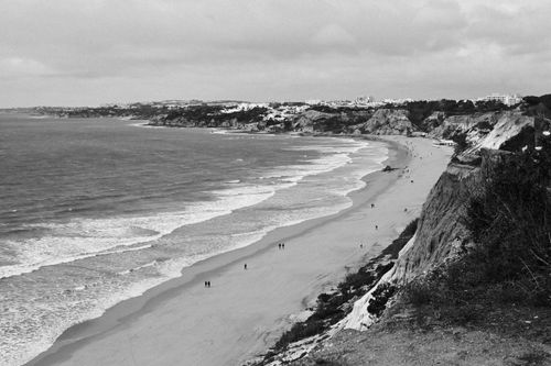 Free Captivating black and white photo of a rugged coastal beach with waves and cliffs. Stock Photo