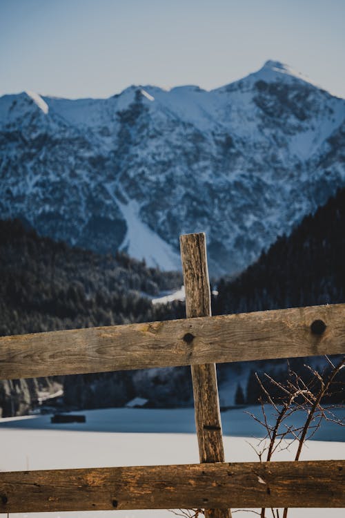A wooden fence with snow covered mountains in the background