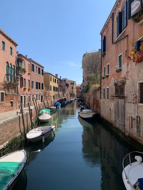 Free A scenic view of a Venetian canal lined with colorful buildings and boats on a clear day. Stock Photo