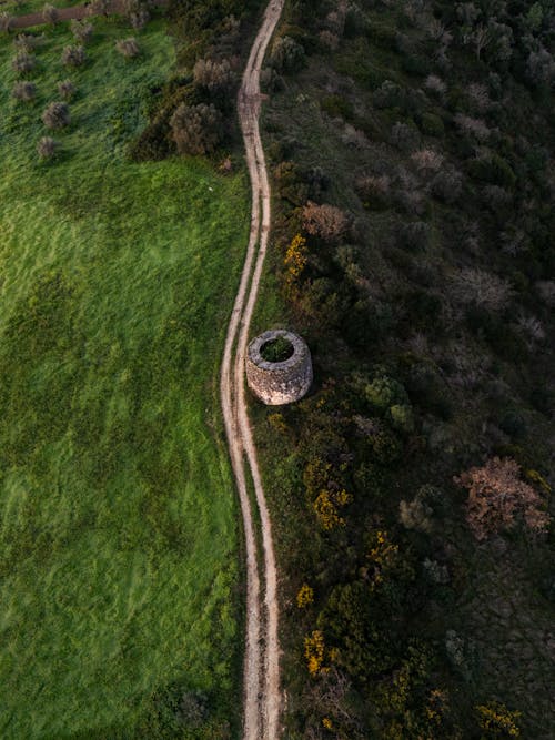 An aerial view of a dirt road and a stone tower