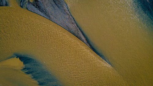 A bird's eye view of a river with yellow and blue water