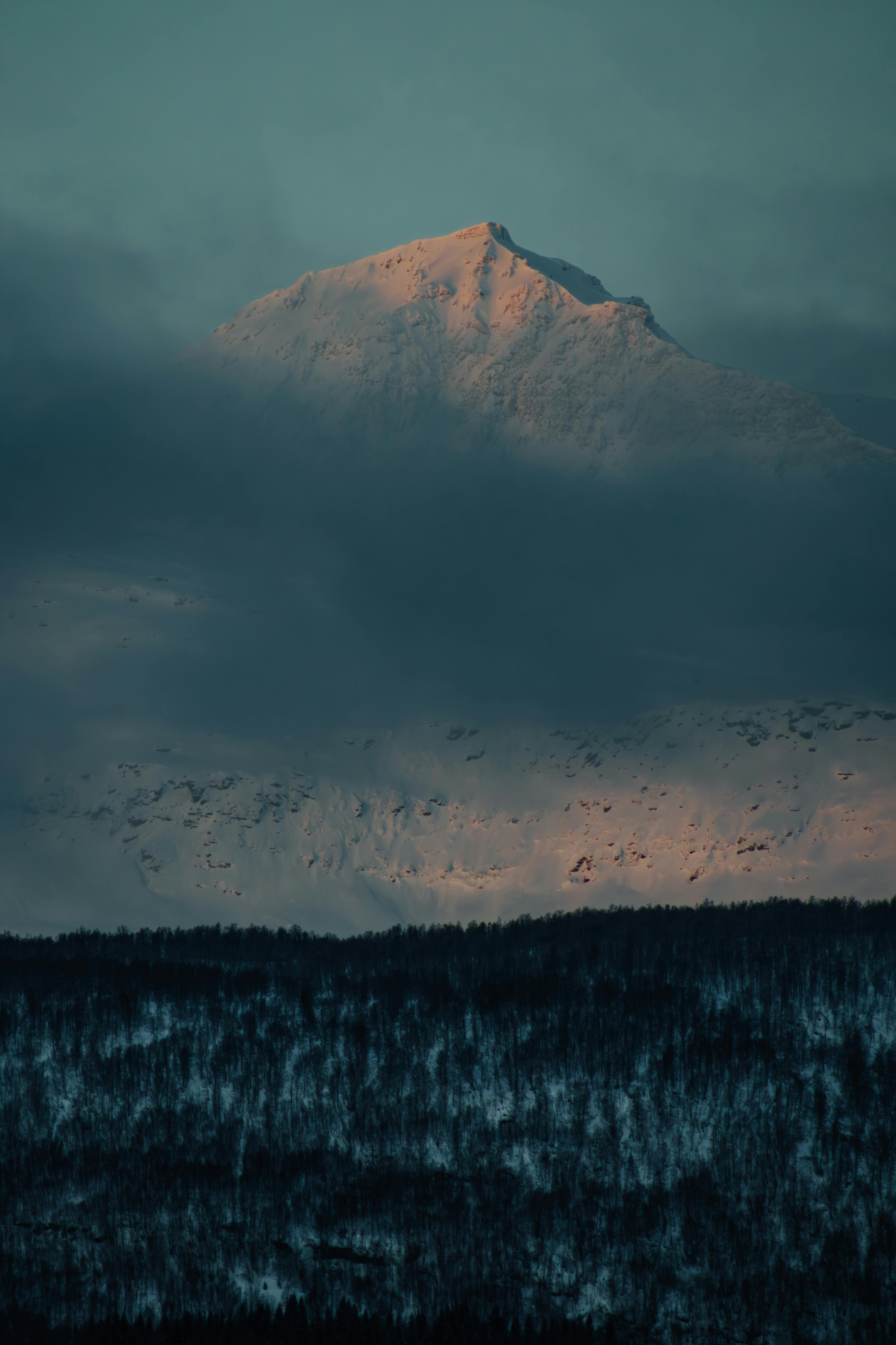 A stunning view of a snow-covered mountain peak in Laksvatn, Troms, Norway at twilight.