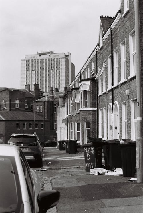 A black and white photo of a street with cars parked