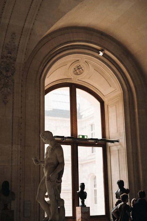 A statue is in the middle of a room with a large arch