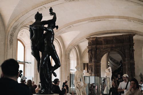 A statue in a museum with people in the background