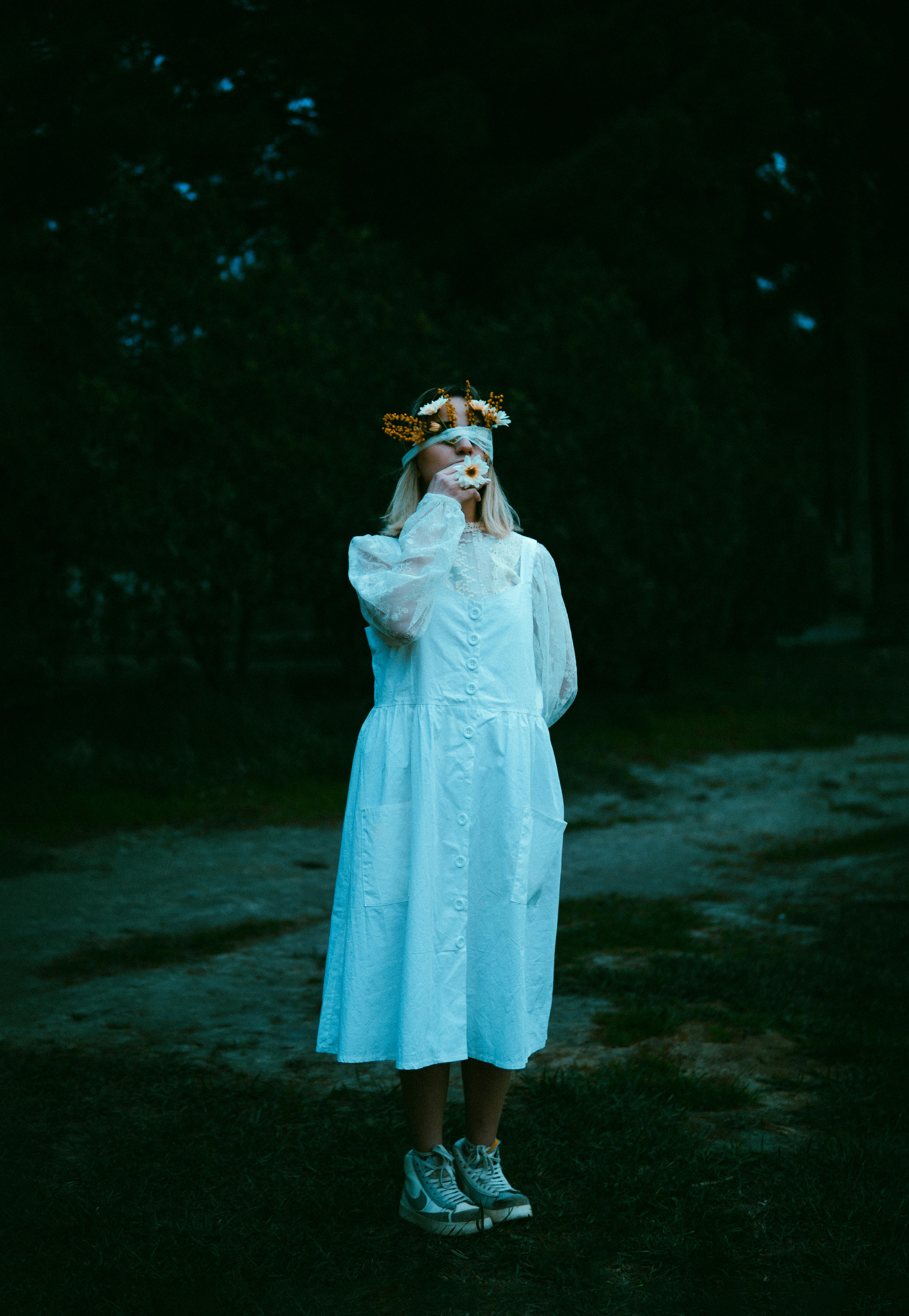 woman in white dress and with flowers under blindfold