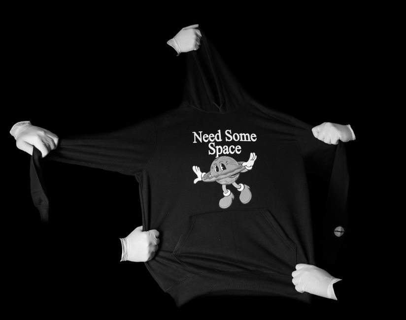 Black and white minimalist photo of a hoodie with hands and 'Need Some Space' print.