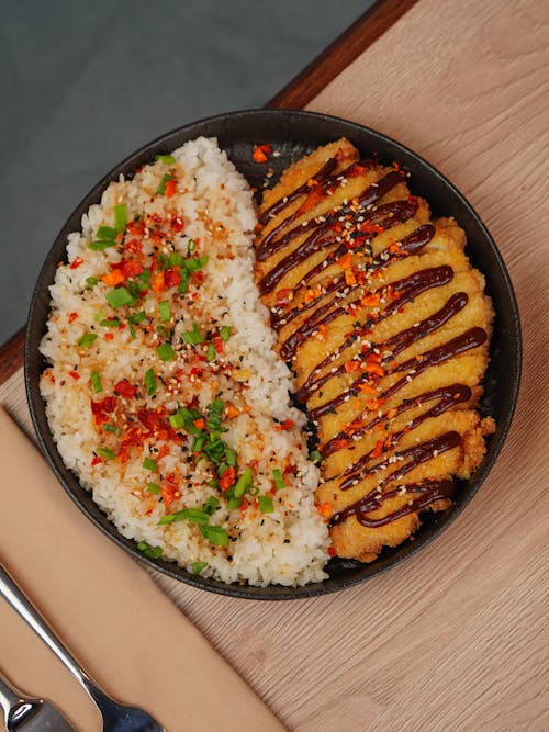 A black plate with rice and meat on top