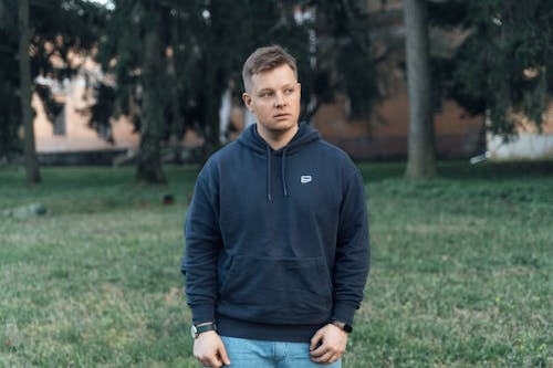 A man in a blue hoodie stands in the grass