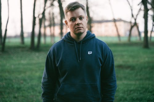 A man in a blue hoodie standing in a field