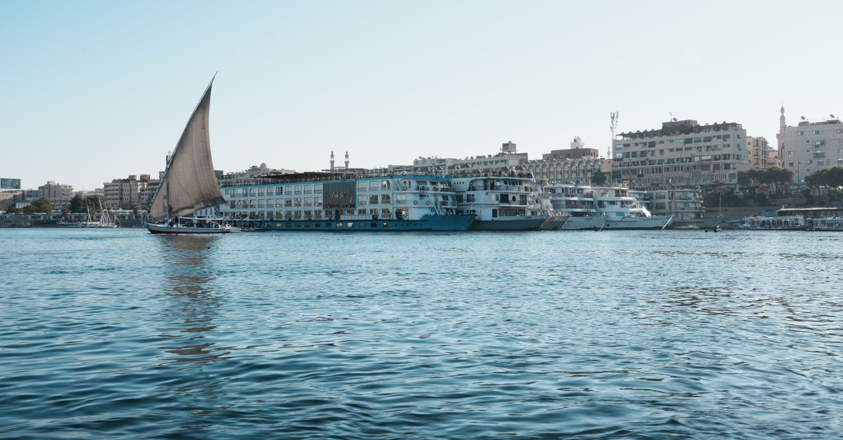 A picturesque view of a traditional sailboat on the Nile River near city waterfronts.