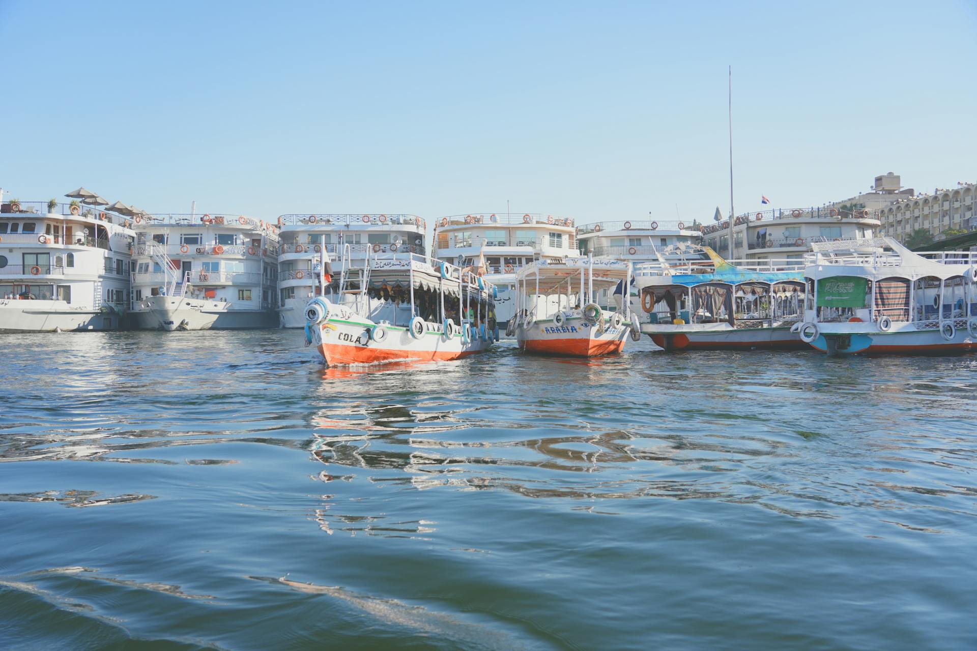A bustling harbor scene with various ferries and boats moored under a clear blue sky.