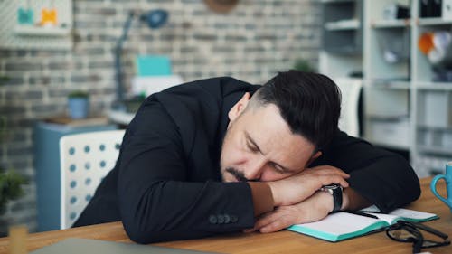 A man in a suit sleeping on a desk