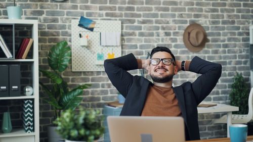 Free Smiling man sits back and relaxes in a stylish modern office setting. Stock Photo