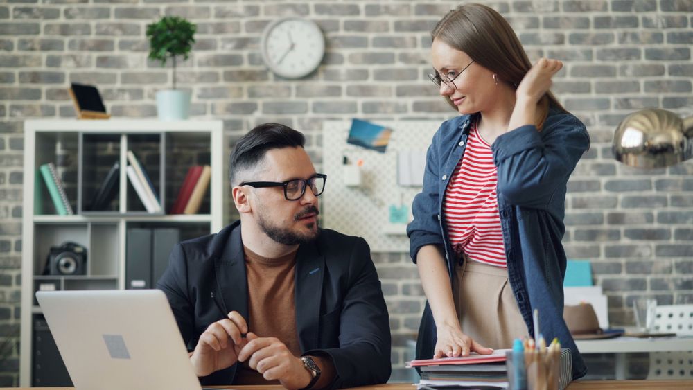 Two colleagues talking over a laptop at a desk — Vitaly Gariev on Pexels