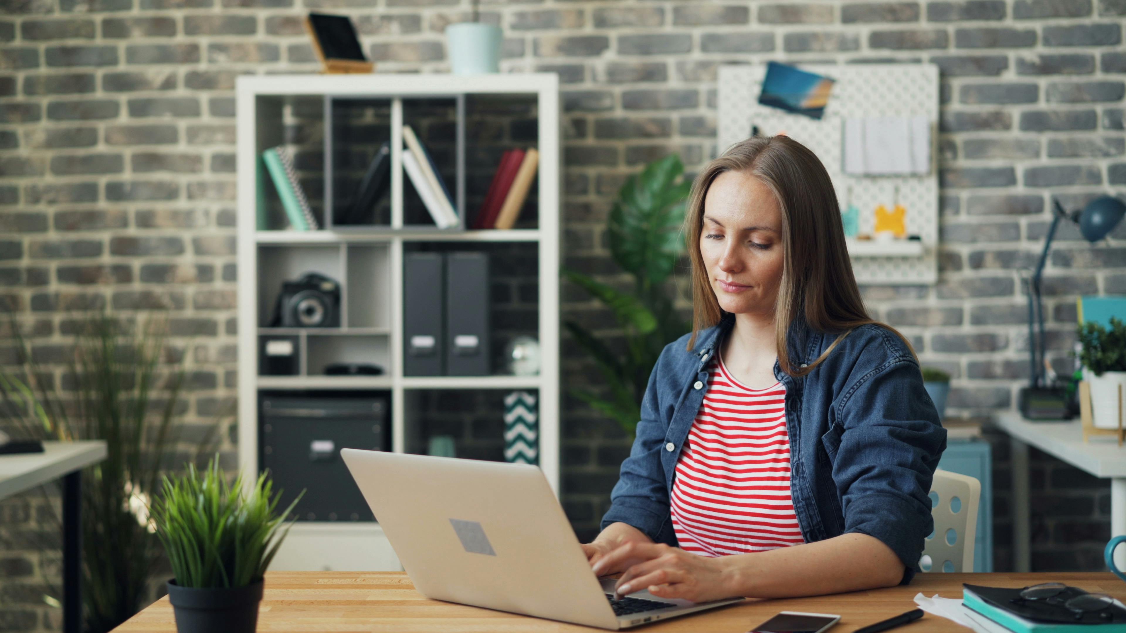 A woman focused on her laptop in a stylish office setting, showcasing productivity.