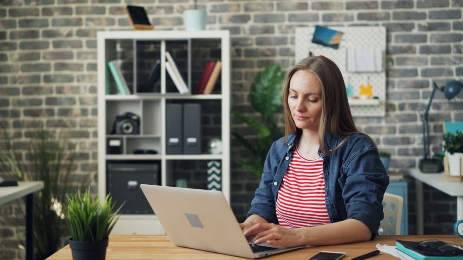 How Password Managers Generate and Store Unique Passwords Securely A woman focused on her laptop in a stylish office setting, showcasing productivity.