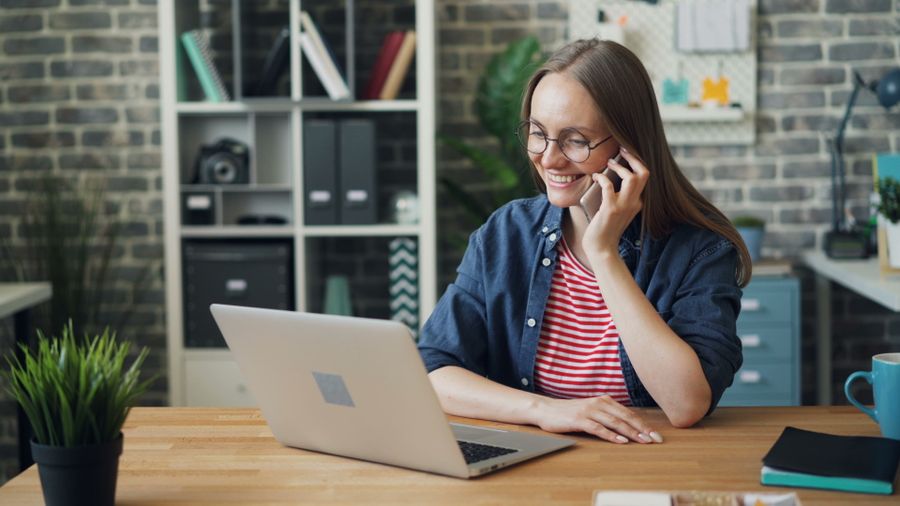 Smiling woman sitting at a desk with phone to ear
