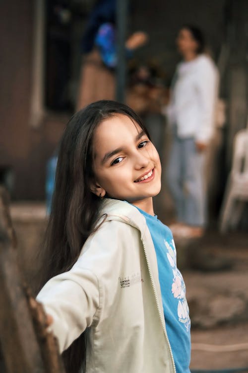 A young girl smiles while standing on a wooden plank