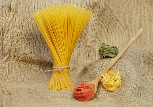 Pasta Beside Brown Wooden Laddle on Brown Knitted Textile