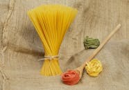 乡村粗麻布织物上摆放着未经烹煮的意大利面和丝带面，呈现出一种美学布局