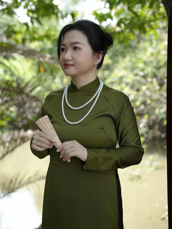 A woman in a green dress holding a fan