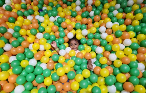 A child is playing in a ball pit filled with colorful balls