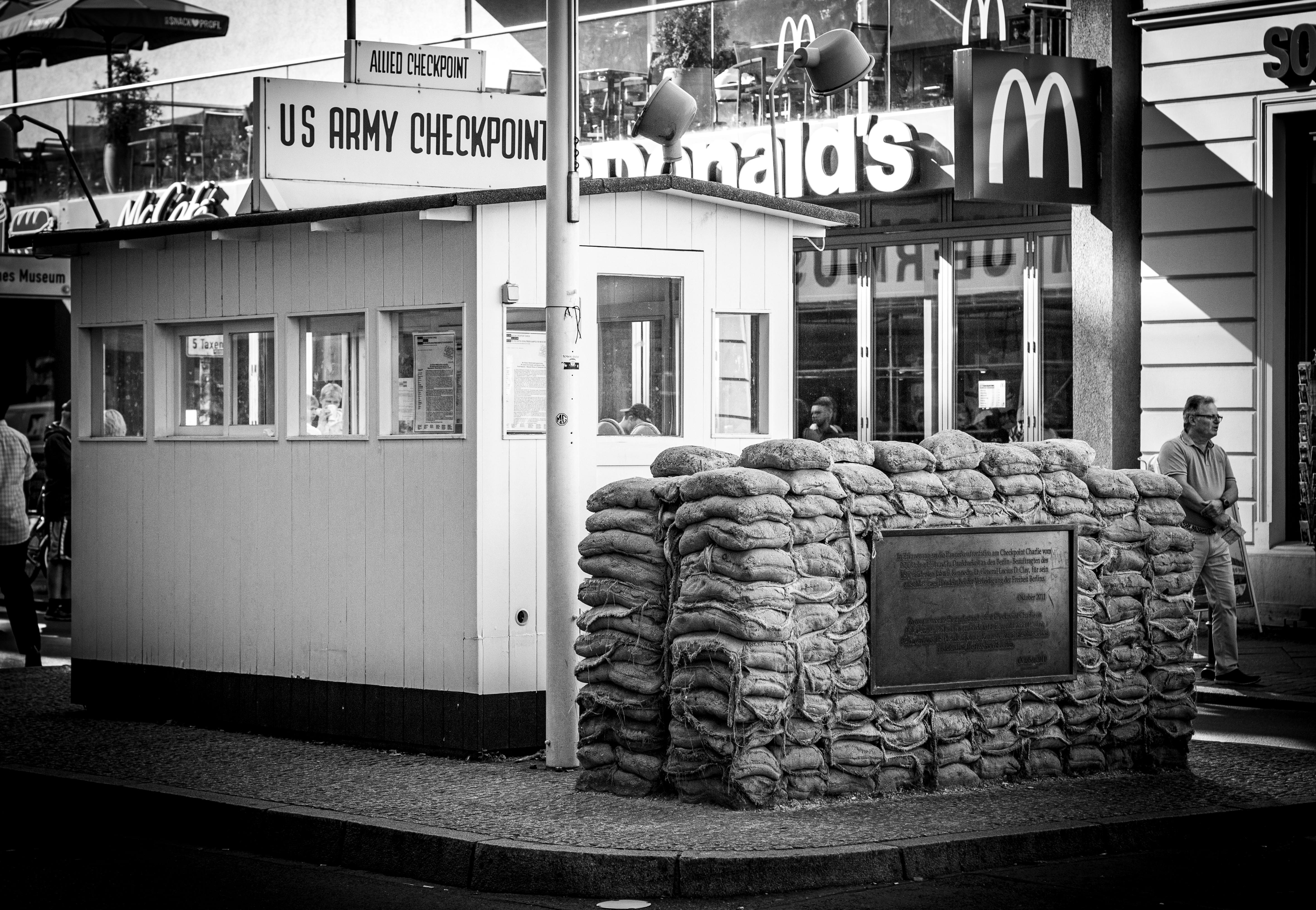 Black and white photo of Checkpoint Charlie, a historic Berlin landmark, showcasing its urban setting.