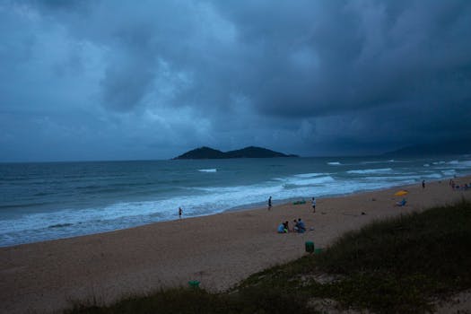 Dramatic evening view of a beach with storm clouds and distant island.