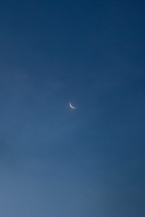 Free A serene crescent moon against a deep blue twilight sky, perfect for calm and contemplation. Stock Photo