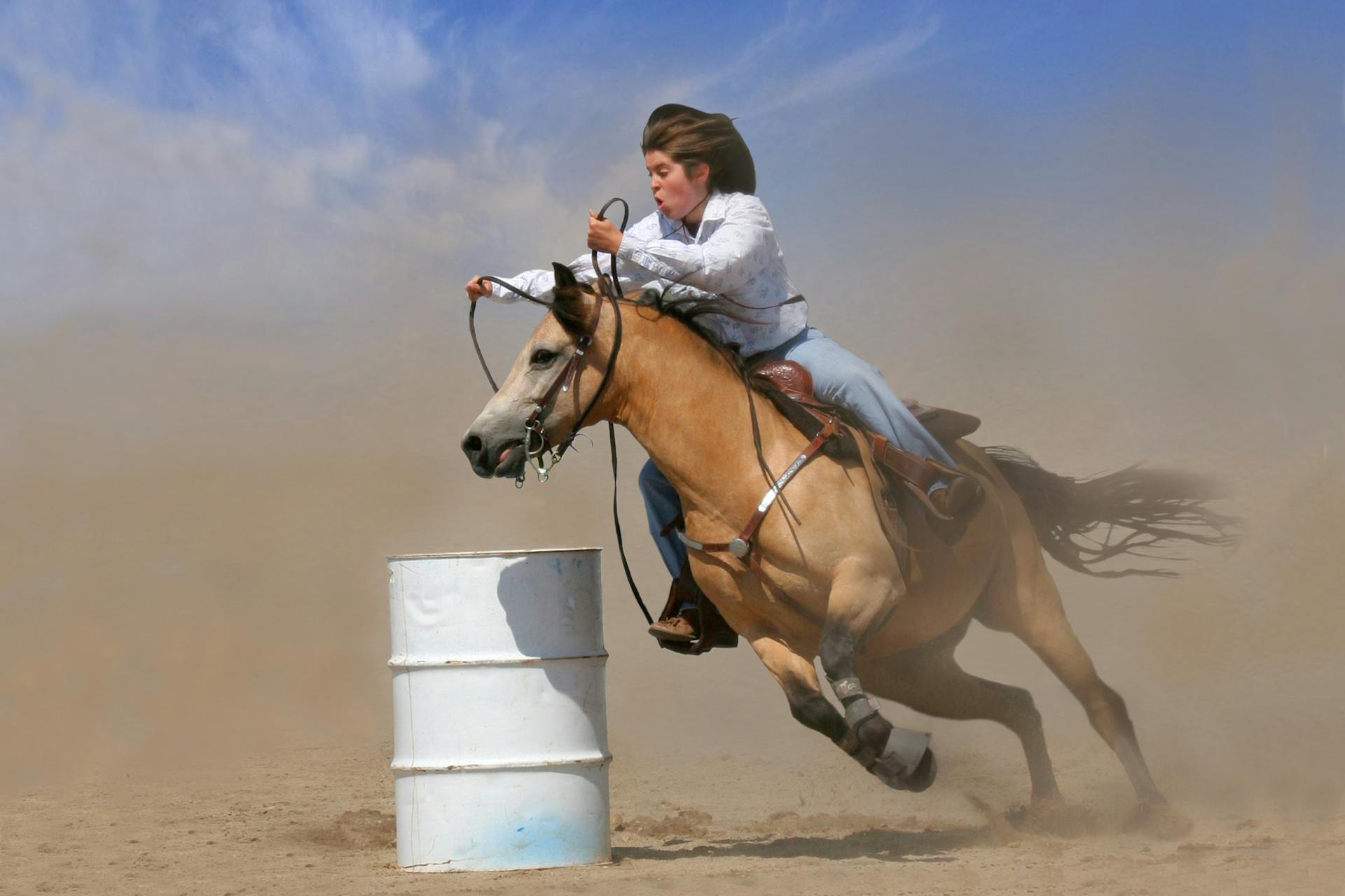 A woman races her horse around a barrel, showcasing speed and skill in an outdoor arena.