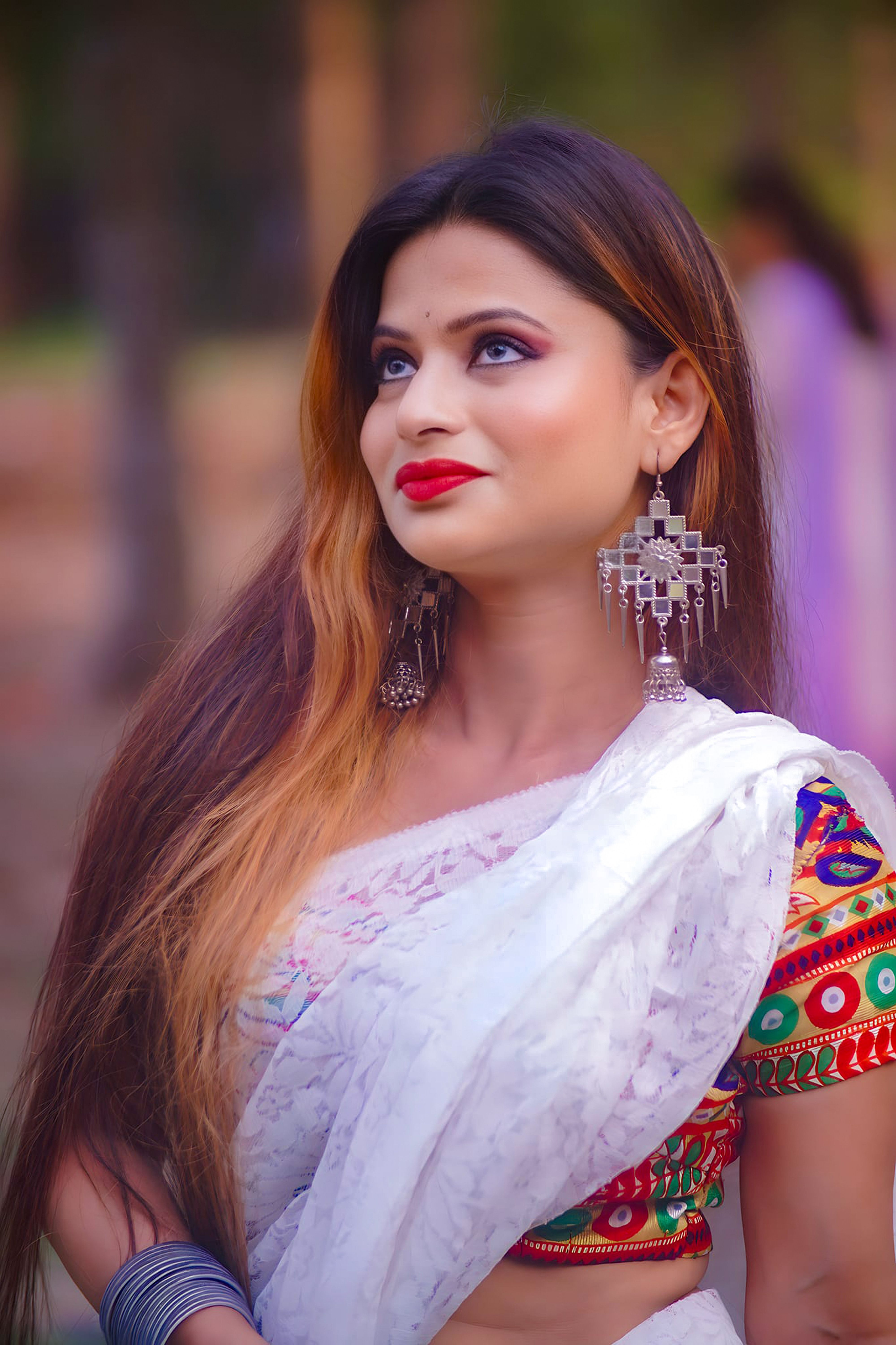 Portrait of a woman in vibrant traditional Indian clothing with intricate earrings, captured outdoors.