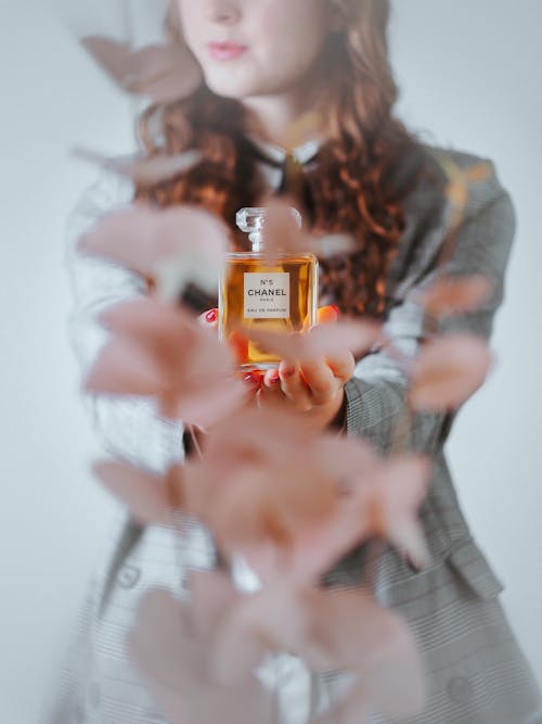 A woman holding a perfume bottle with pink flowers