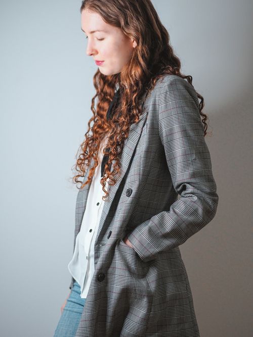 Free Stylish woman posing indoors with plaid jacket and curly hair, Paris. Stock Photo