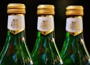 这三个绿色玻璃瓶配有金色盖子，非常适合庆祝场合