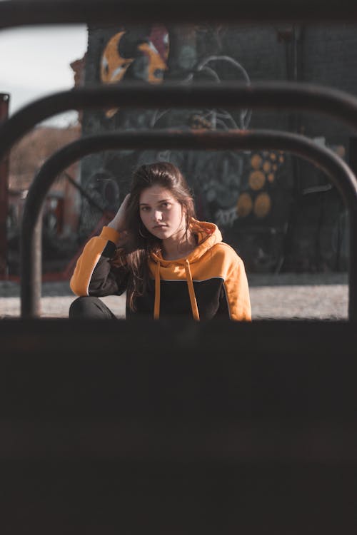 Foto De Mujer Sentada En Una Sudadera Con Capucha Negra Y Naranja Sosteniendo Su Cabello