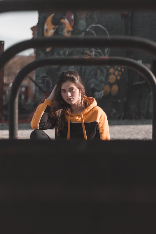 Free Photo of Sitting Woman in Black and Orange Hoodie Holding Her Hair Stock Photo
