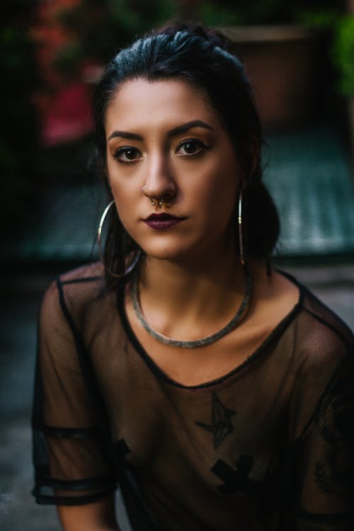 Woman Wearing Black See Through Blouse and Silver-colored Hoop Earrings Looking Straight