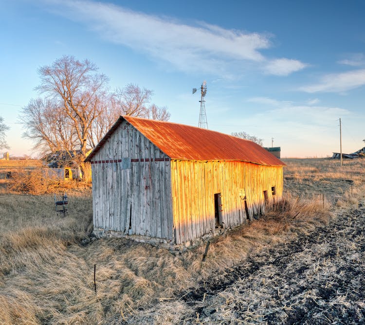 Crumbling Wooden Shed With Rusty Roof At Sunset